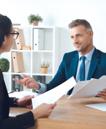 Business,Partners,With,Papers,Discussing,Work,At,Workplace,In,Office