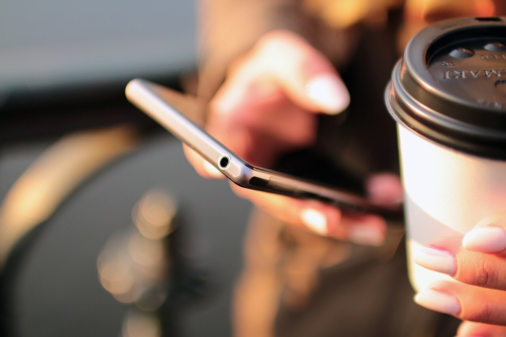 Kahve yanında telefon kullanan eller