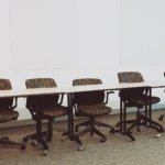 Uzun bir toplantı masası etrafındaki ofis sandalyeleri