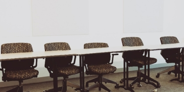 Uzun bir toplantı masası etrafındaki ofis sandalyeleri