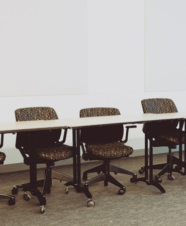 Uzun bir toplantı masası etrafındaki ofis sandalyeleri